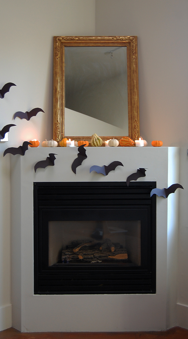 minimalist halloween decor and halloween mantle using pumpkins, candles, and construction paper bats