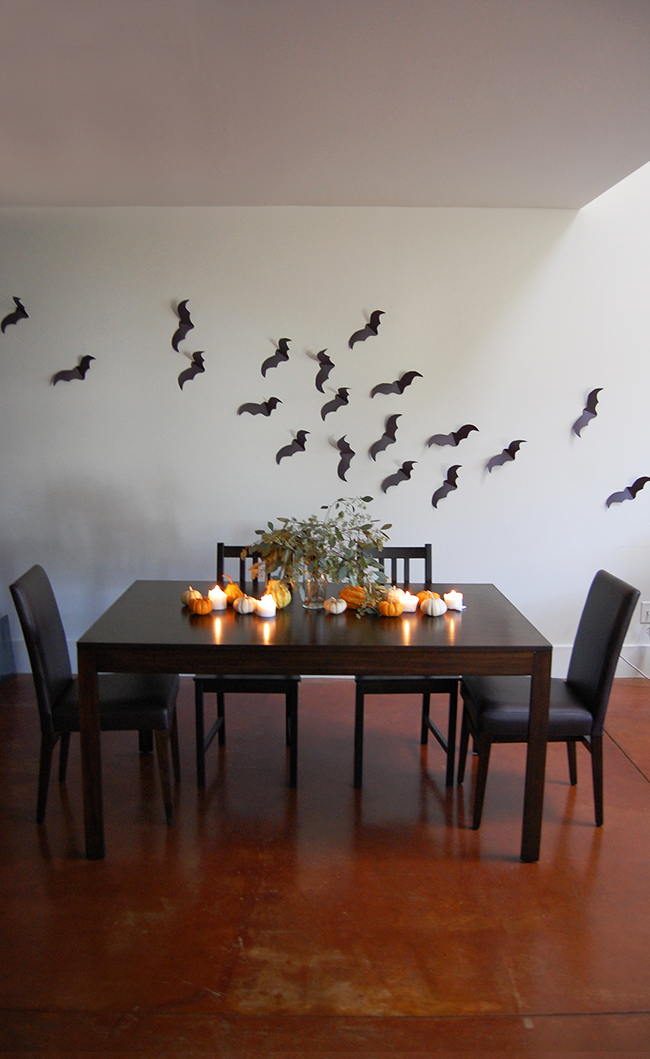 minimalist halloween decor and halloween tablescape using pumpkins, candles, and construction paper bats