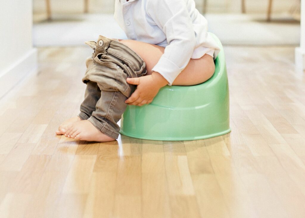 Child sitting on a potty chair - How to Clean a Toddler Potty Chair