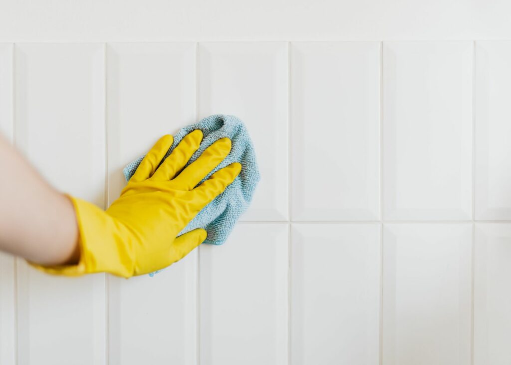 Person cleaning shower tiles - How to Clean Shower Tiles Without Scrubbing 