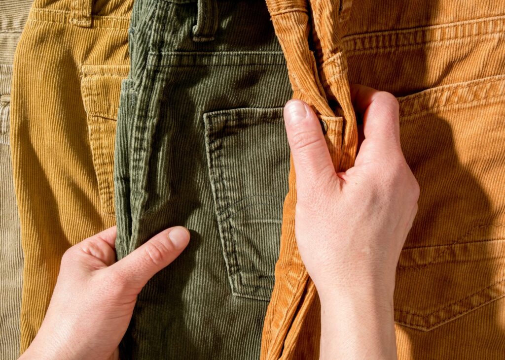 Close-up hands touch corduroy trousers - How to Wash Corduroy