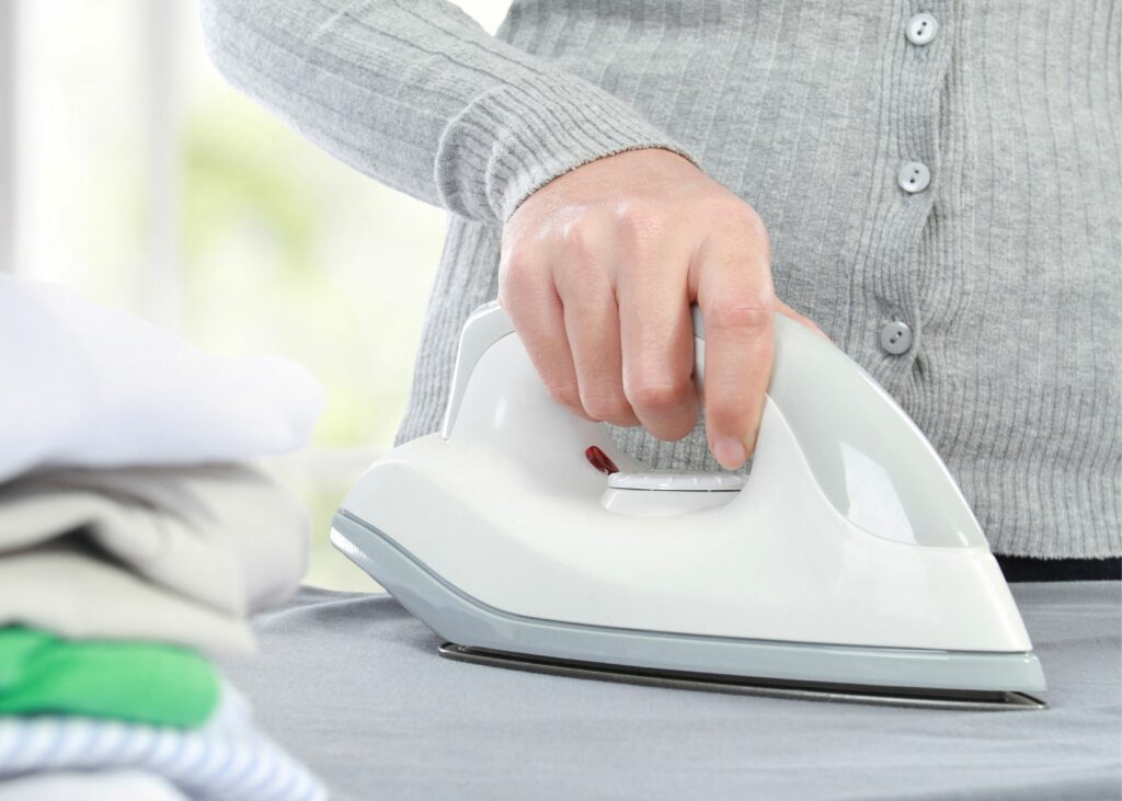 Lady ironing clothes on iron board - steam iron vs. dry iron